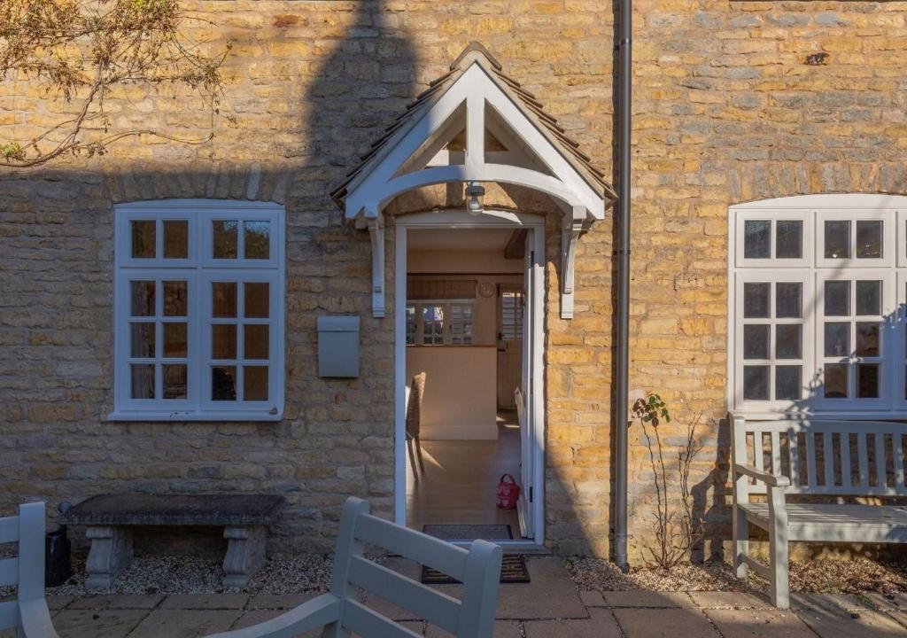 un ingresso a un edificio in mattoni con porta bianca di Jasmine Cottage - 2 Bedroom in Heart of Bourton! a Bourton on the Water