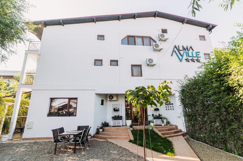 a white house with a table and chairs at AlmaVille Mamaia in Mamaia Sat/Năvodari