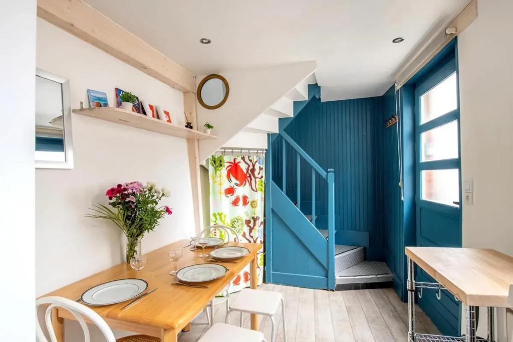 une salle à manger avec une table en bois et une porte bleue dans l'établissement Charmant appartement à Étretat, 30 m² avec cuisine équipée, à Étretat
