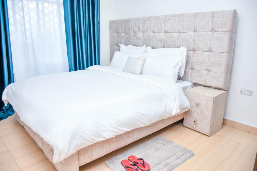 Home of comfort في ناكورو: غرفة نوم بسرير كبير مع ملاءات ووسائد بيضاء