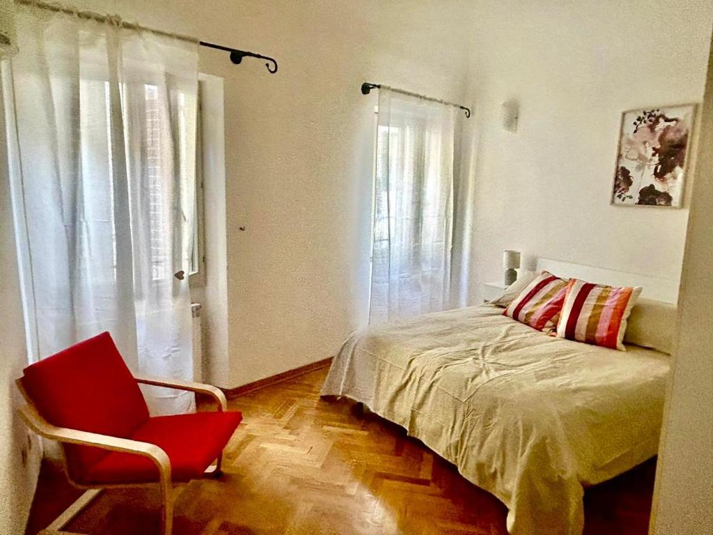 a bedroom with a bed and a red chair at Da Tommaso in centro in Prato