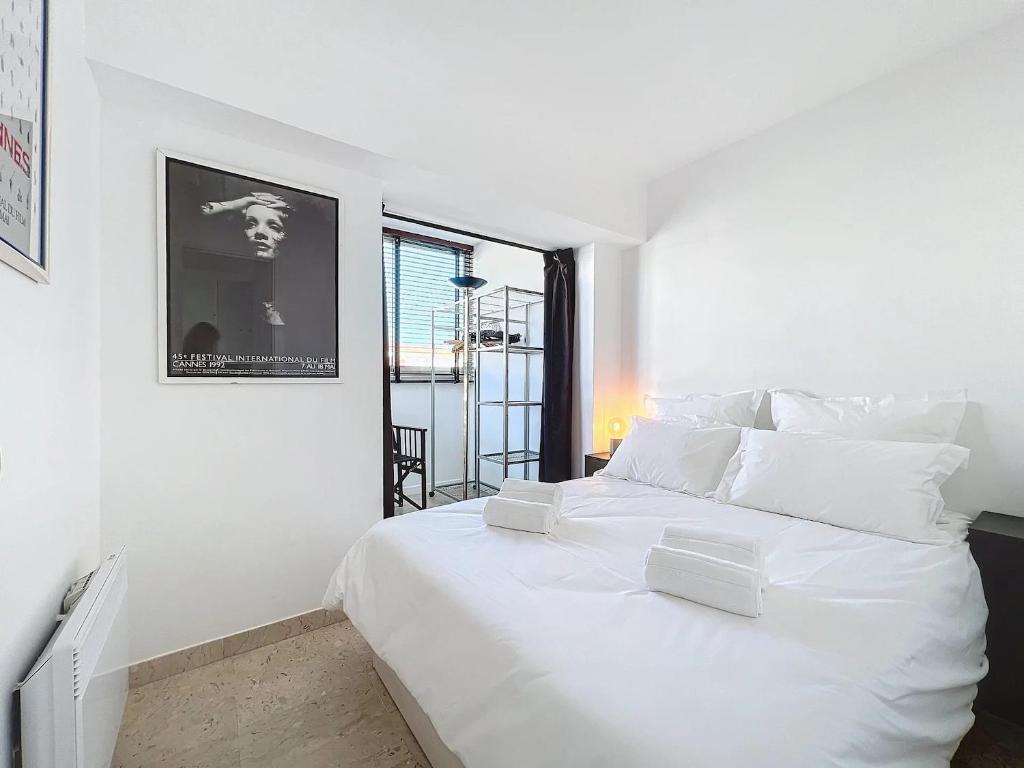 Un dormitorio blanco con una gran cama blanca y una ventana. en 2P Between Croisette Beaches and Antibes Street, en Cannes