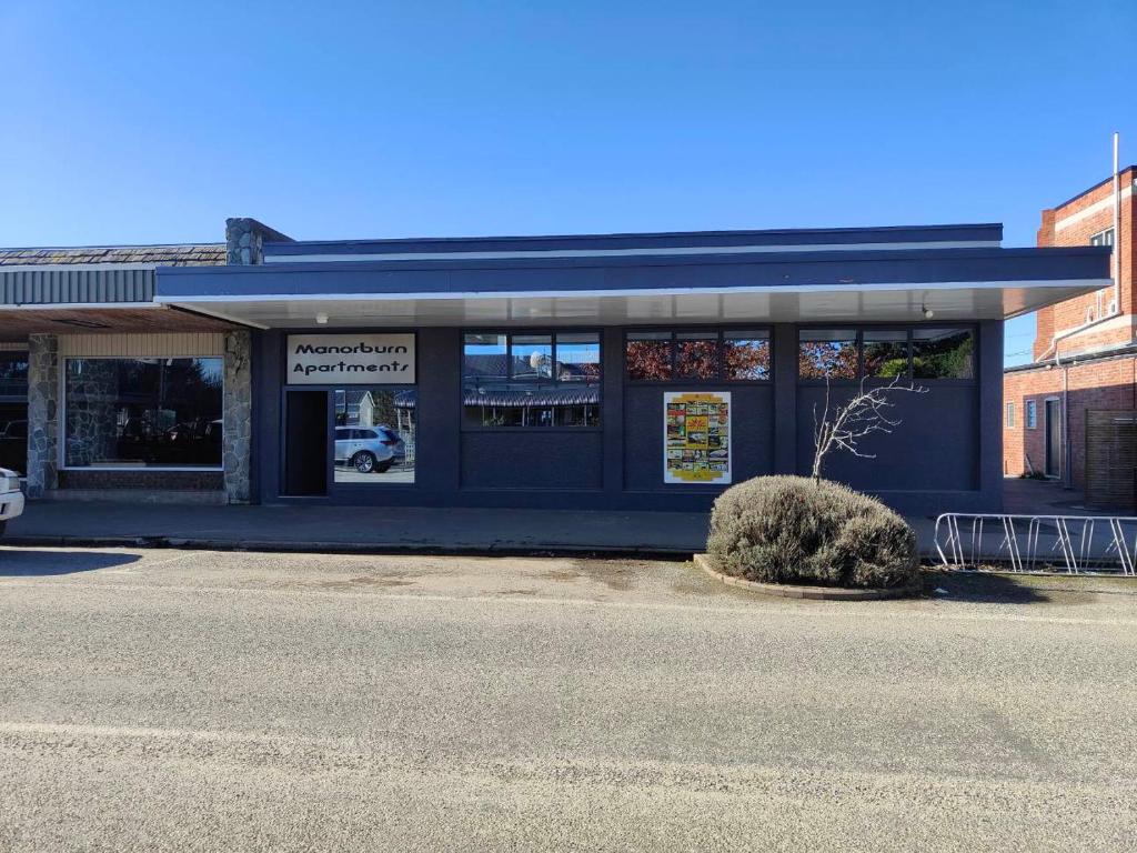 a blue building with a bush in front of it at Manorburn Apartments Luxury Studio Apartment Central Otago in Ranfurly