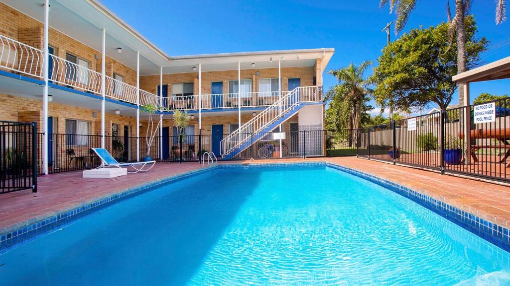 a swimming pool in front of a building at Coasters 18 - steps from downtown Sawtell in Sawtell