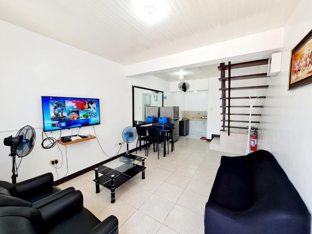 a living room with a couch and a tv on a wall at Calapan Transient House L12 in Calapan