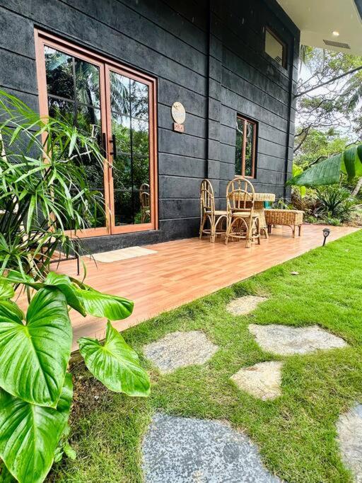 a house with a wooden deck with a table and chairs at Casita Ysla Tiny Home with garden kitchen wifi 2 scooters in El Nido