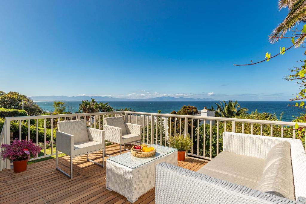 a deck with chairs and a table with a view of the ocean at Davley House, St James Kalk Bay in Cape Town