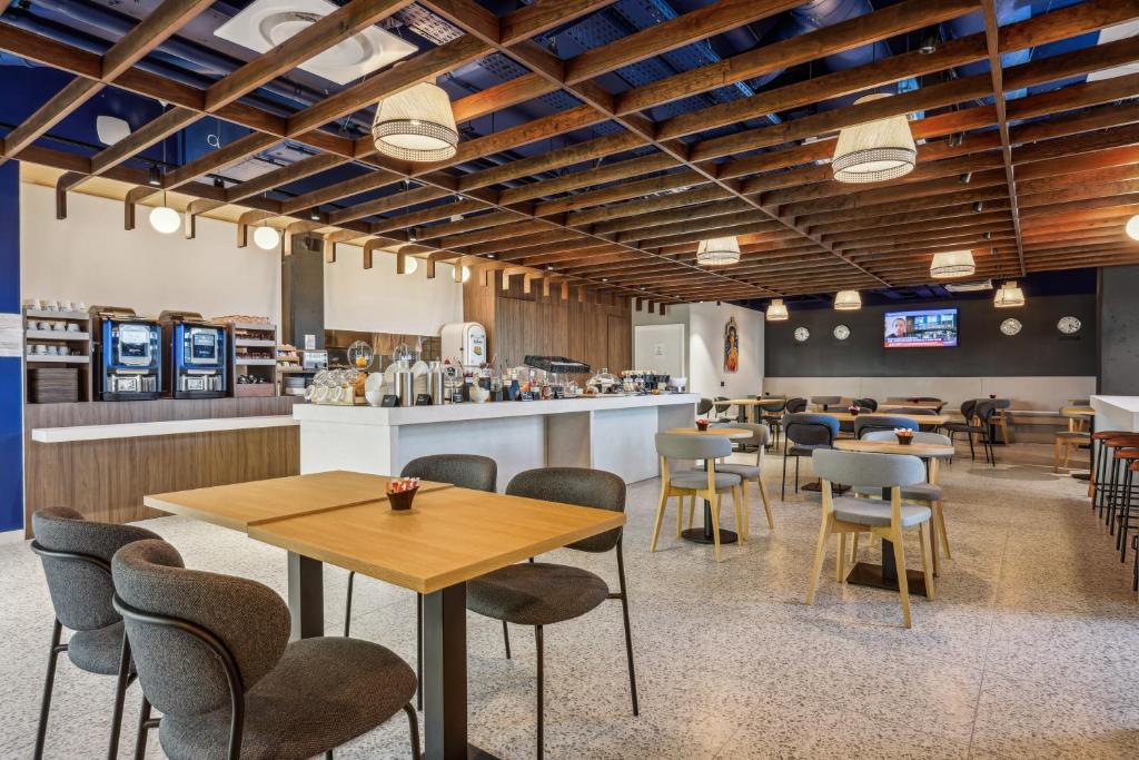 セリにあるHôtel AKENA Serris - Val d'Europeの木製の天井、テーブルと椅子のあるレストラン