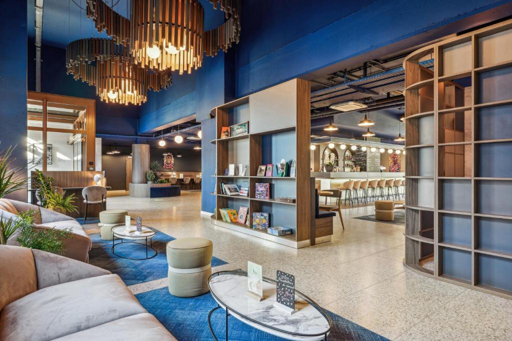 セリにあるHôtel AKENA Serris - Val d'Europeのソファ、テーブル、本棚のある図書室