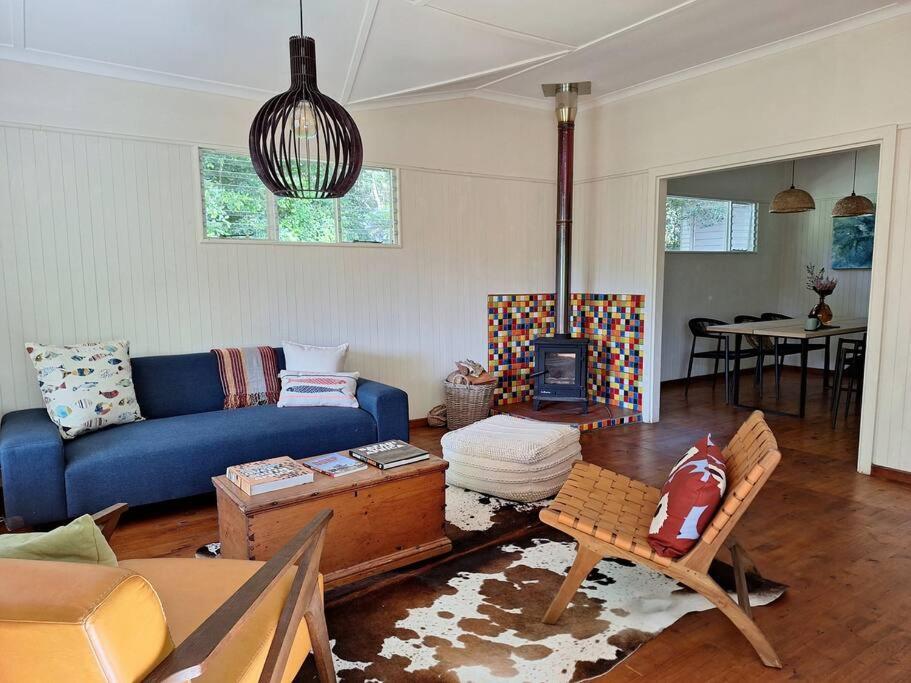 a living room with a blue couch and a table at Whispering Woods Cottage in Natureʼs Valley