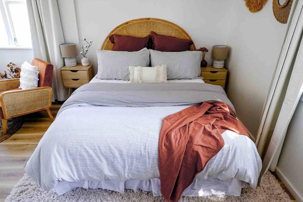 a bedroom with a large bed with a wooden headboard at Waikanae Beach Escape - with outdoor bath! in Waikanae