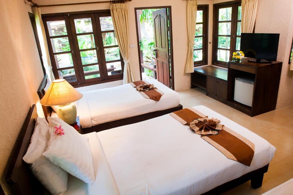 a hotel room with two beds and a television at Montien House - SHA Plus in Chaweng