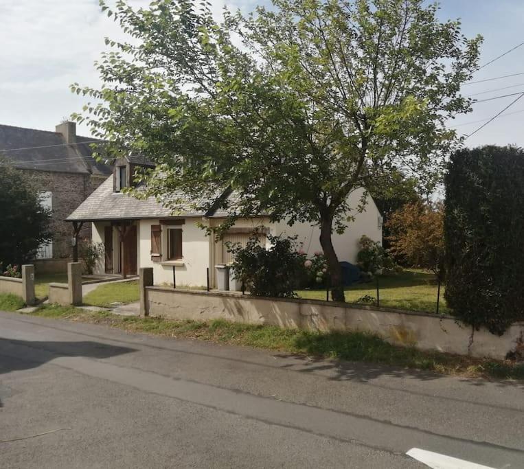 une maison blanche avec un arbre sur le côté d'une rue dans l'établissement Maison de 100m2 récemment rénovée Cancale, à Cancale