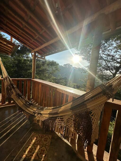 a hammock on a deck with the sun in the background at Chalé Biribó in Conceição do Mato Dentro