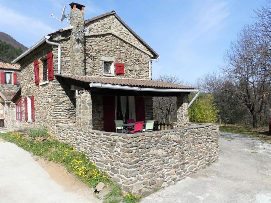 une maison en pierre avec des fenêtres rouges et un mur en pierre dans l'établissement Gîte de 2 ou 3 personnes la Bergerie, à Gravières