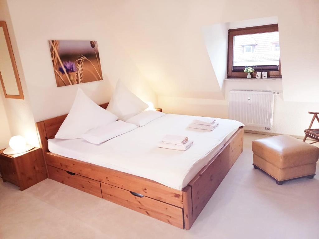 Un dormitorio con una gran cama de madera con sábanas blancas. en Maisonette Ferienwohnung - Stuth Barth, en Barth