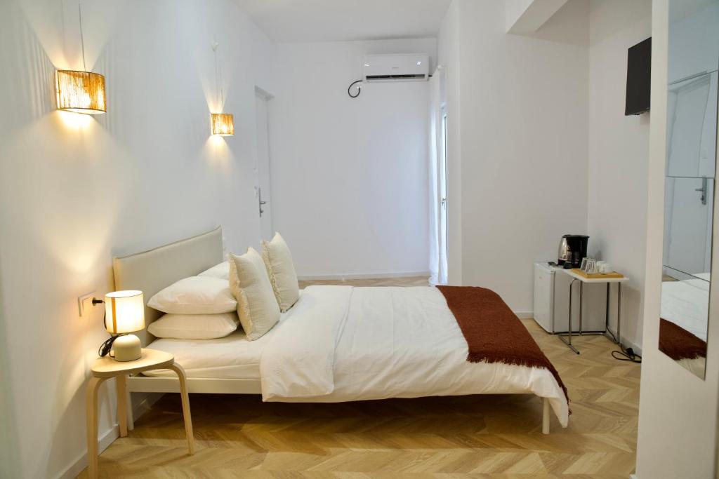 a bedroom with a bed with white sheets and pillows at Tzatziki Boutique Rooms in Kavala