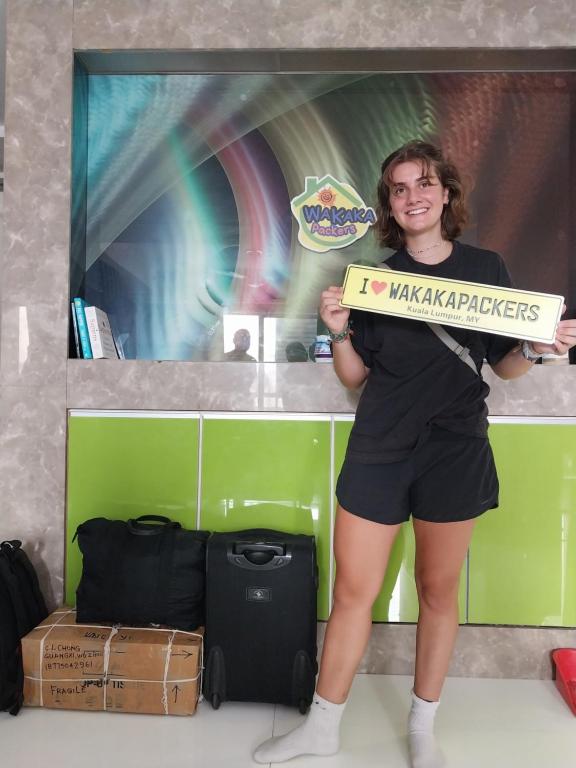 a woman holding a sign that says make a mistake at WakakaPackers in Kuala Lumpur