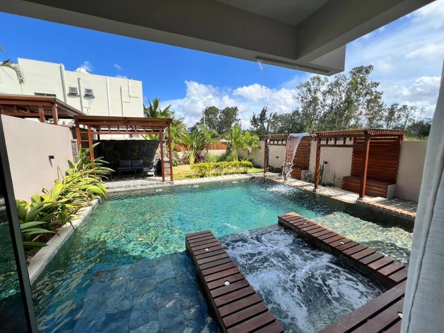 a swimming pool with benches in front of a house at Villa Cookie le Coquin, 3 chambre au centre de Grand Baie, jacuzzi in Grand Baie