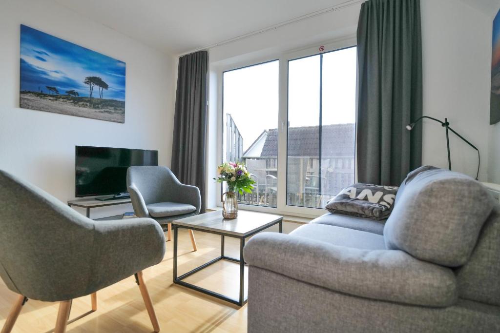 a living room with a couch and two chairs and a television at HAUSTIERFREI - Ferienwohnung Meerfarbig Zingst - GLASFASER -Balkon - Parkplatz - Fahrradschuppen - zentral&ruhig - E-Ladesäule - Waschtrockner - Nichtraucher - allergikerfreundlich in Zingst