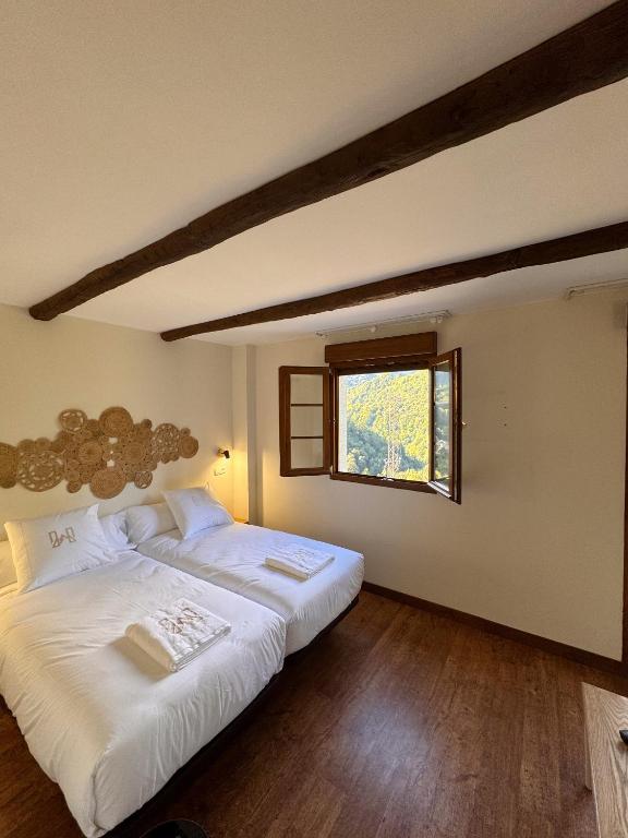 two beds in a room with a window at Hotel Rural Valle de Cuaña in Santibáñez de Murias