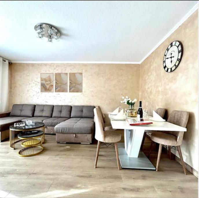 a living room with a couch and a table and a clock at Appartement à 10 min de Strasbourg in Strasbourg