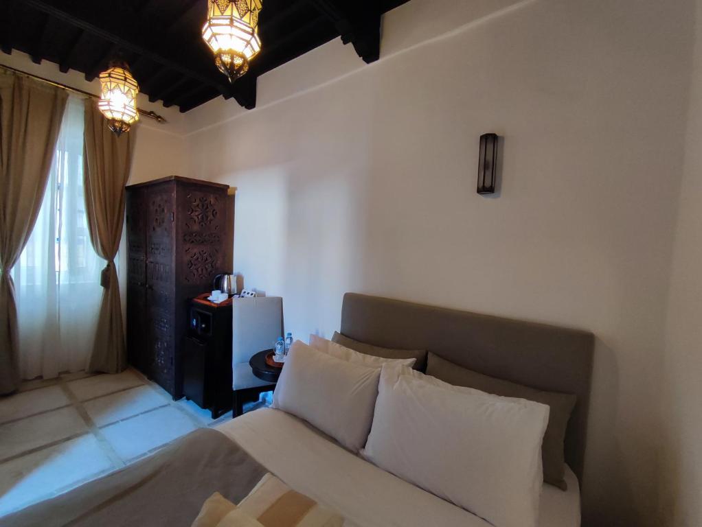 a bedroom with a bed with white pillows at Riad de charme L'Oasis d'Essaouira - Chambre Luxe en Terrasse in Essaouira