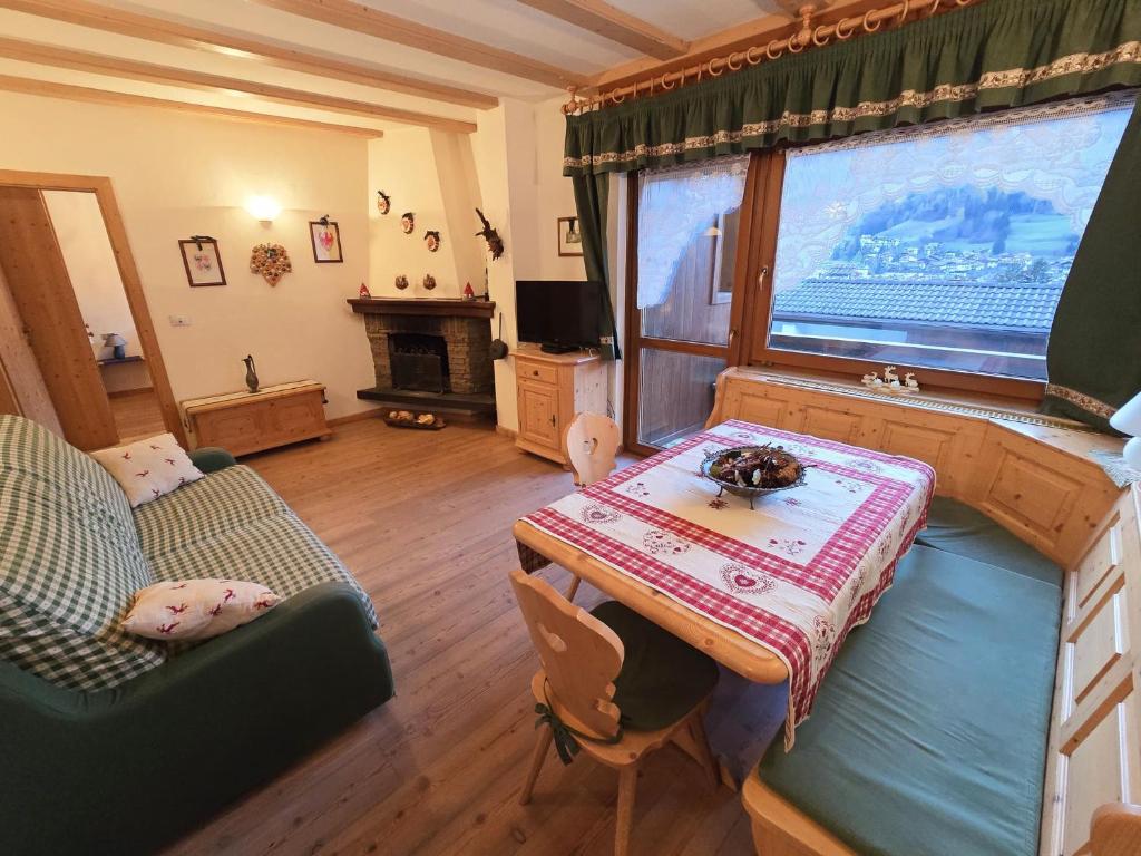 a living room with a table and a large window at Sogno sulle Dolomiti - Alpine Stay Apartments in Moena