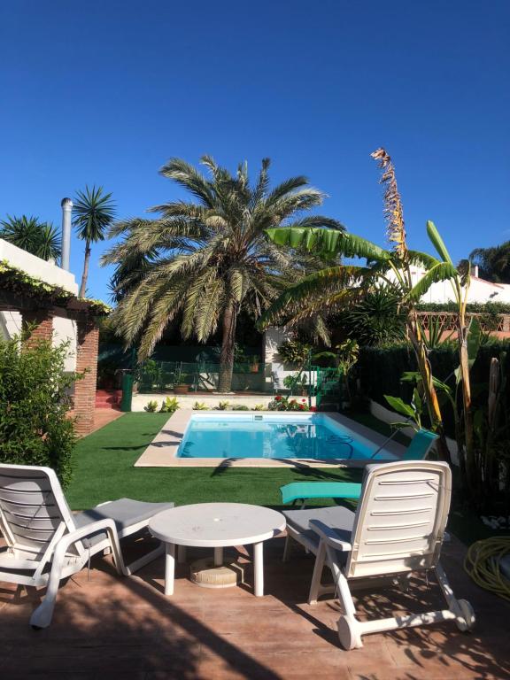 a group of chairs and a table and a pool at CHALET en la PLAYA CON PISCINA in Marbella