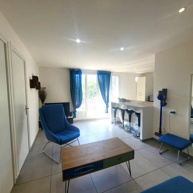 un salon avec une table et des chaises bleues dans l'établissement Élégant 3 Chambres avec Parking, à Grenoble