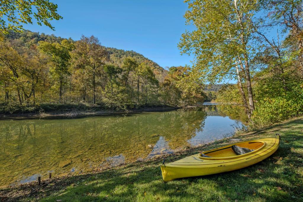 a yellow canoe sitting on the side of a river at River Song Retreat - Right on the River! in Great Cacapon
