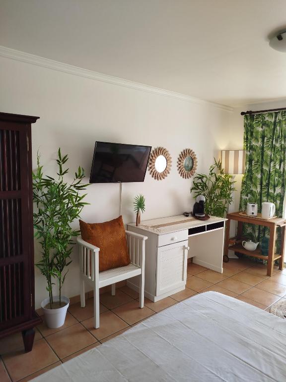 una camera da letto con scrivania e TV a parete di Bambou Suite vue mer à 50 m de la plage et de la piscine a Sainte-Luce