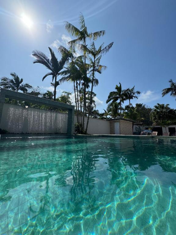a swimming pool with turquoise water and palm trees at Villa's Boraceia in Boracéia
