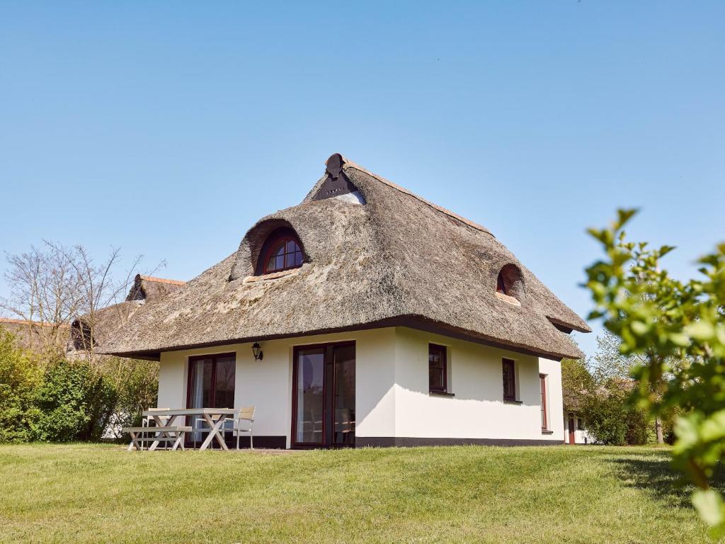 una casa con tetto in paglia e tavolo da picnic nel cortile di Ferienhaus mit tropischem Pool & Spa a Dobbin-Linstow