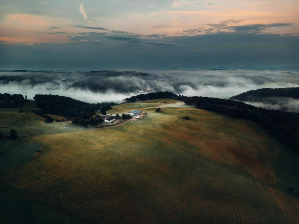 an aerial view of a field with fog in the valley at Ferienwohnung Ostwind in Schüller
