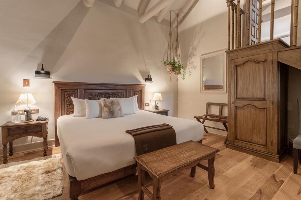 a bedroom with a large white bed and wooden furniture at Antigua Casona San Blas in Cusco
