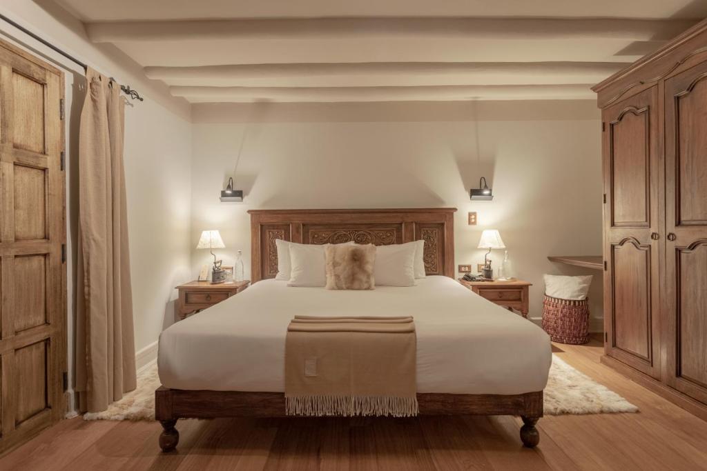 a bedroom with a large white bed and wooden cabinets at Antigua Casona San Blas in Cusco