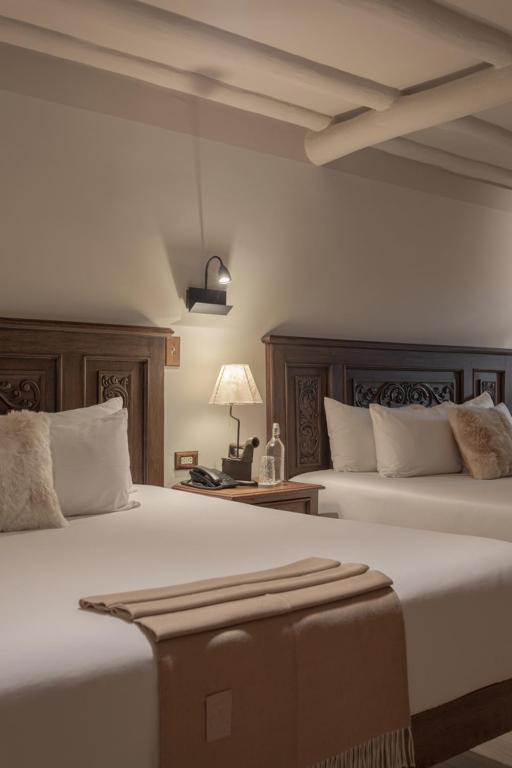 a bedroom with two beds and a table with a lamp at Antigua Casona San Blas in Cusco
