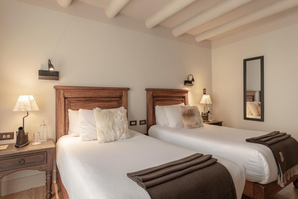 two beds in a room with two tables and lamps at Antigua Casona San Blas in Cusco