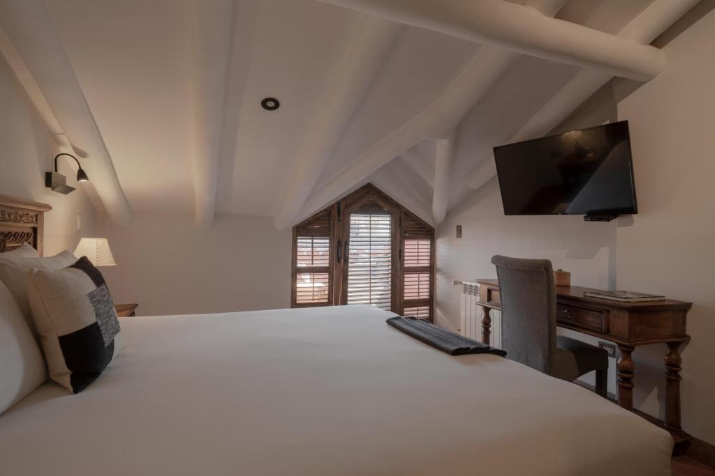 a bedroom with a bed and a desk and a television at Antigua Casona San Blas in Cusco