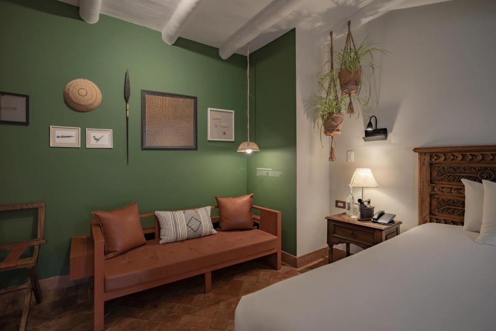 a bedroom with green walls and a bed and a couch at Antigua Casona San Blas in Cusco