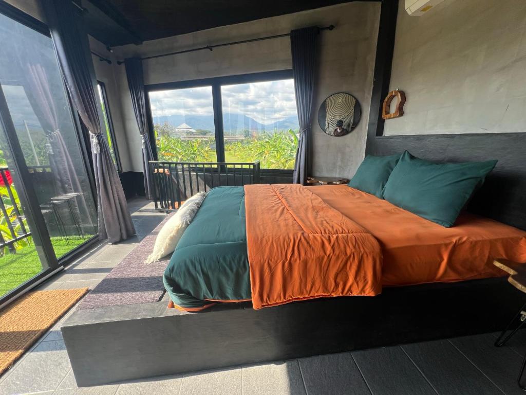 a bed in a room with a large window at KUBU BLACK HOUSE in Jembrana