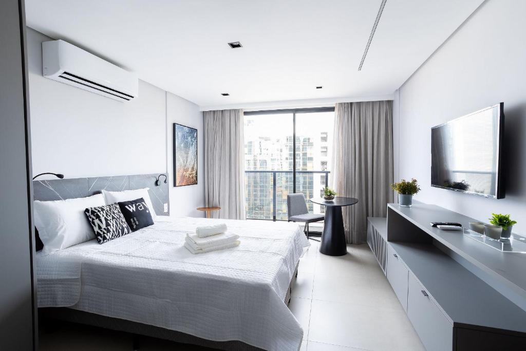 a white bedroom with a large bed and a television at Way Tambaú #H6 - Triplo Deluxe por Carpediem in João Pessoa