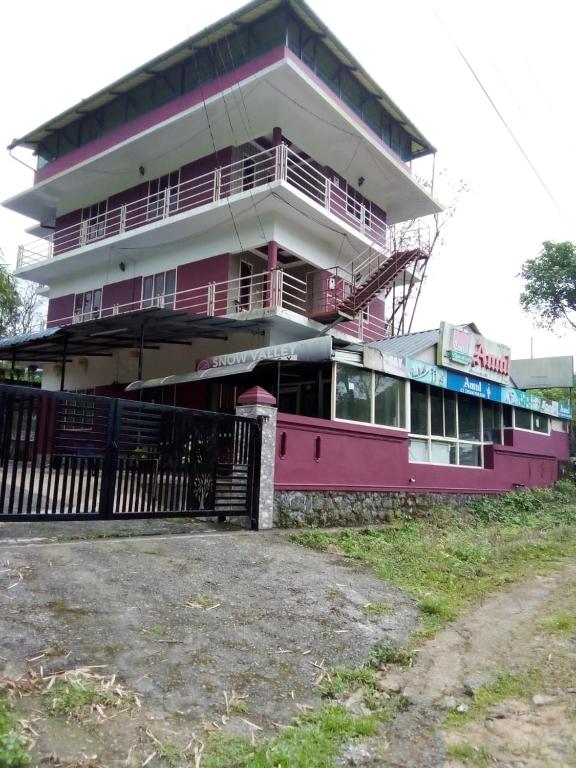 a pink building with a fence in front of it at SNOWVALLEY RESIDENCY in Vagamon