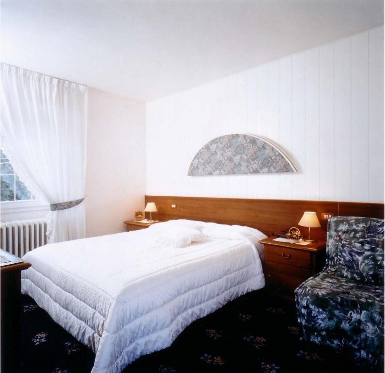 a bedroom with a large bed and a chair at Hotel Bruna in Lizzano in Belvedere