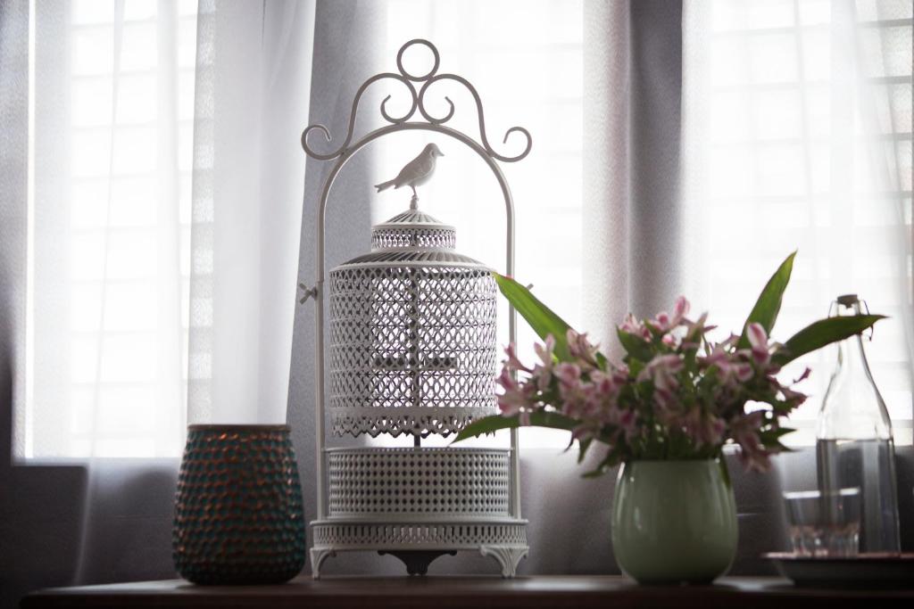 a bird cage on a table with a vase of flowers at Jawi Peranakan Mansion in George Town