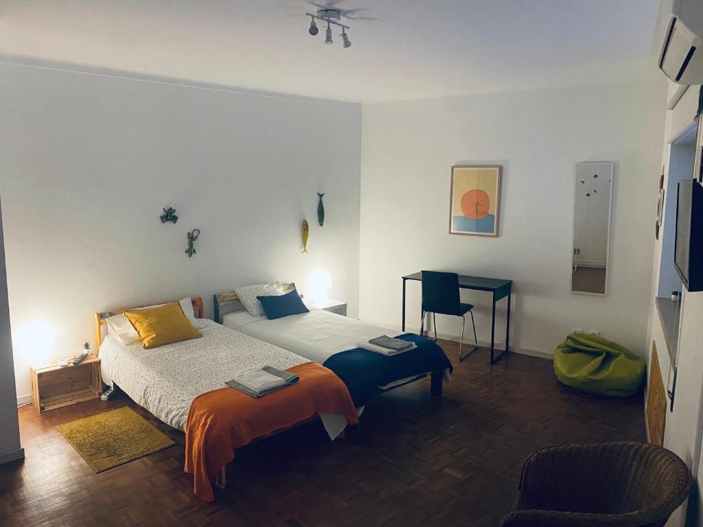 a bedroom with a bed and a table and a chair at Bordallo's Lodge - centro Caldas da Rainha in Caldas da Rainha