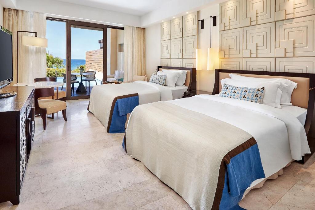 a hotel room with two beds and a television at The Romanos, a Luxury Collection Resort, Costa Navarino in Romanu