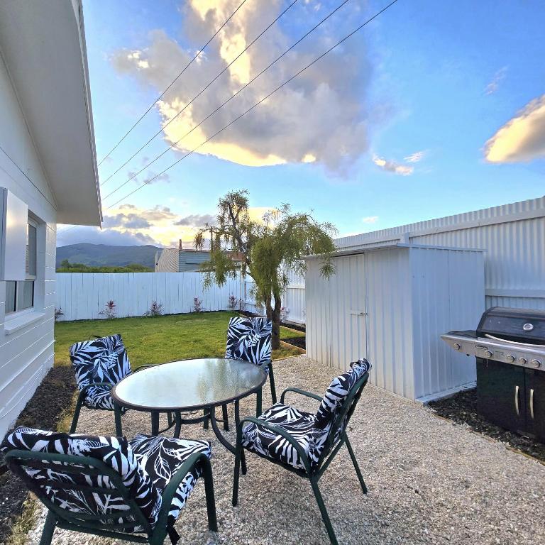 patio con sedie, tavolo e grill di Pasture Views Cottage a Riwaka