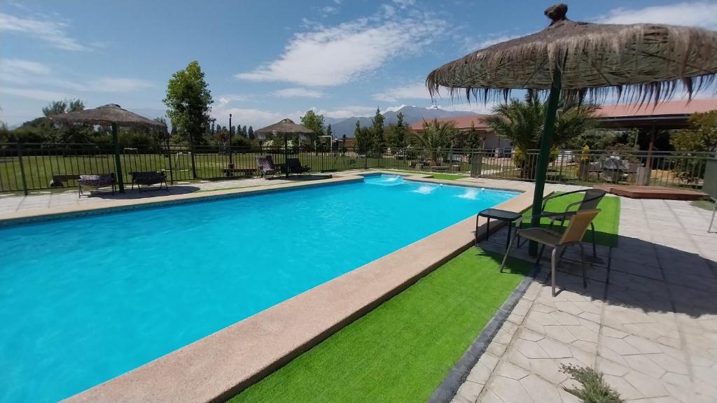a swimming pool with an umbrella and green grass at Escapada romántica de día con tinaja caliente opcional in Pirque
